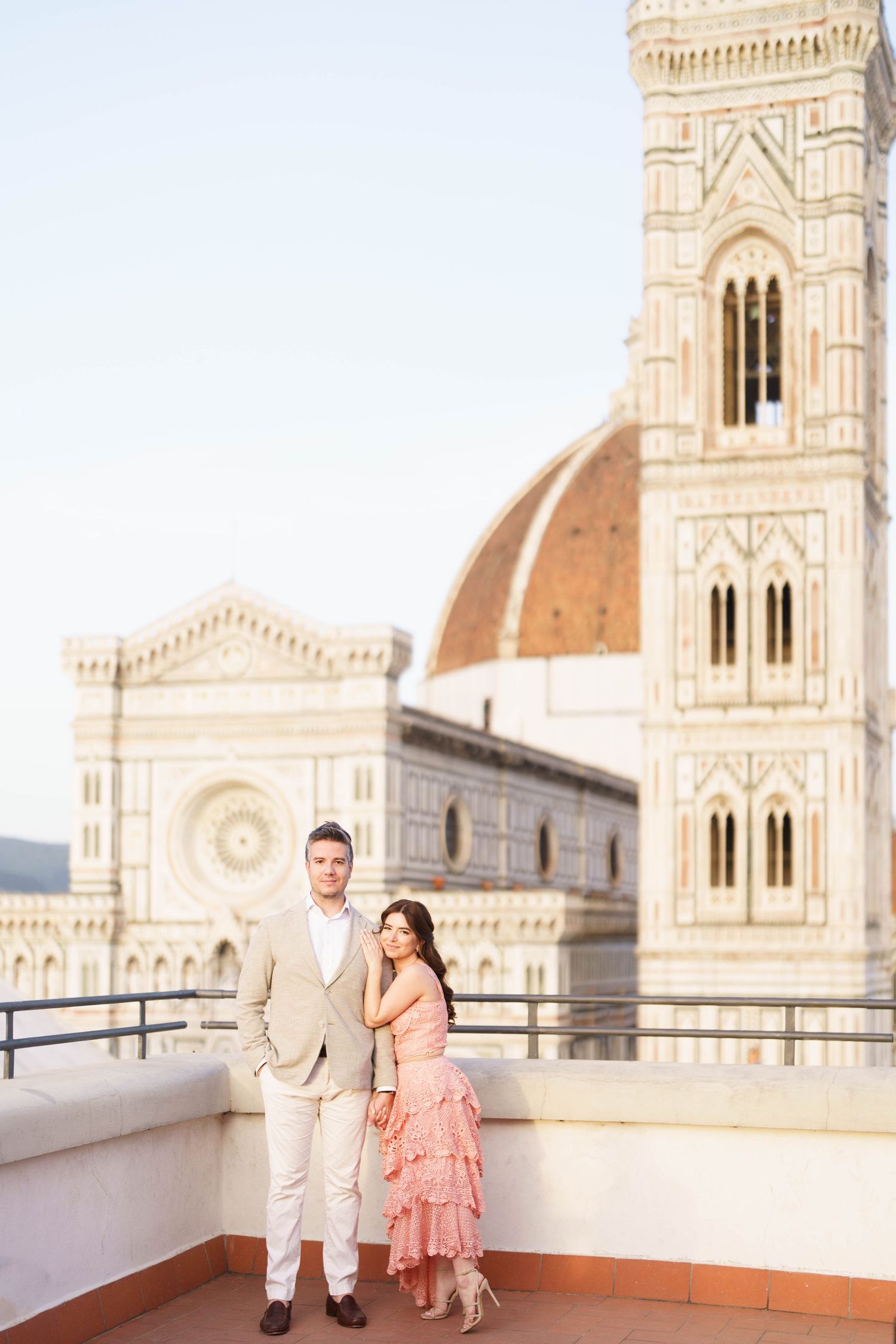 Couple enjoying a romantic moment on a rooftop terrace overlooking Florence Cathedral and its iconic dome in Italy.