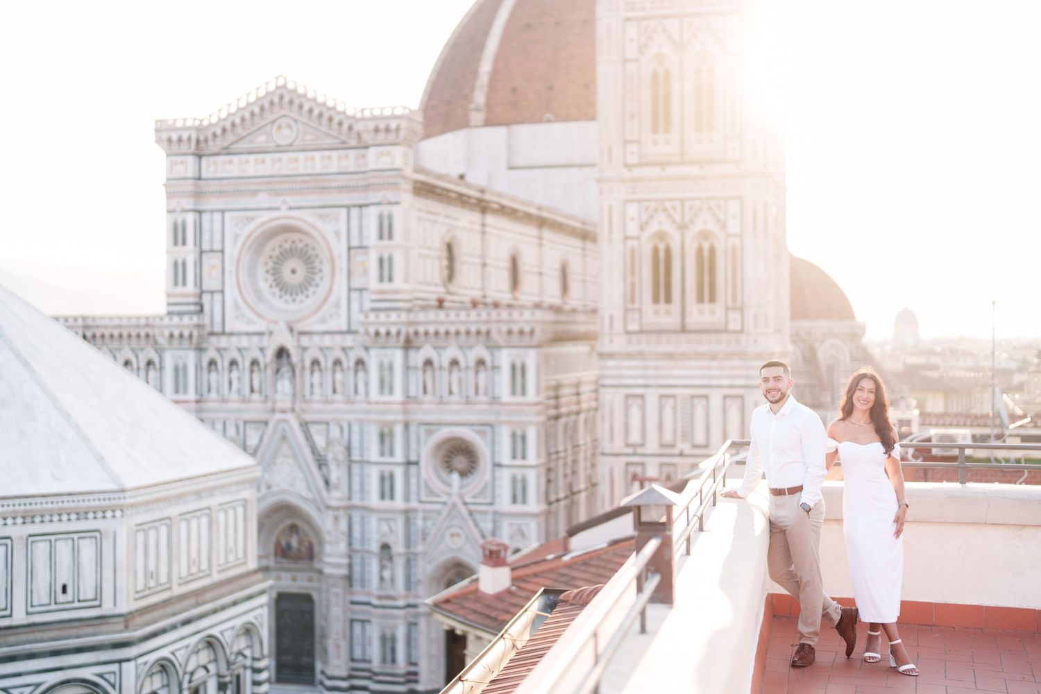 Florence Cathedral and Baptistery glowing in soft sunlight with tourists walking through the historic piazza.