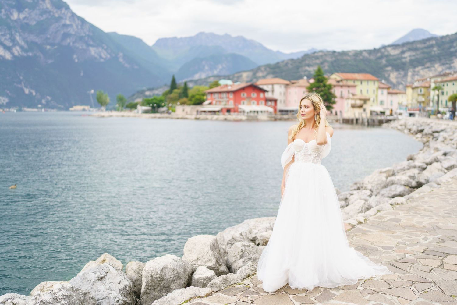 A scenic lakeside wedding photoshoot with mountains and coastal rocks along Lake Garda in Italy.