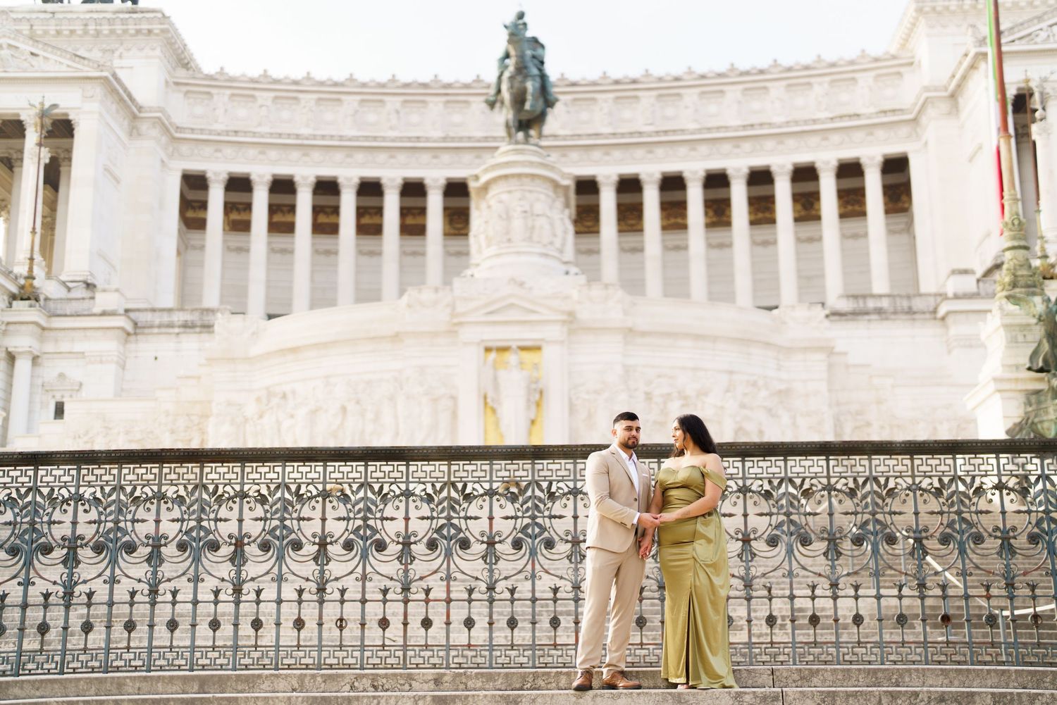 Couple posing romantically in front of the Altar of the Fatherland in Rome, Italy.