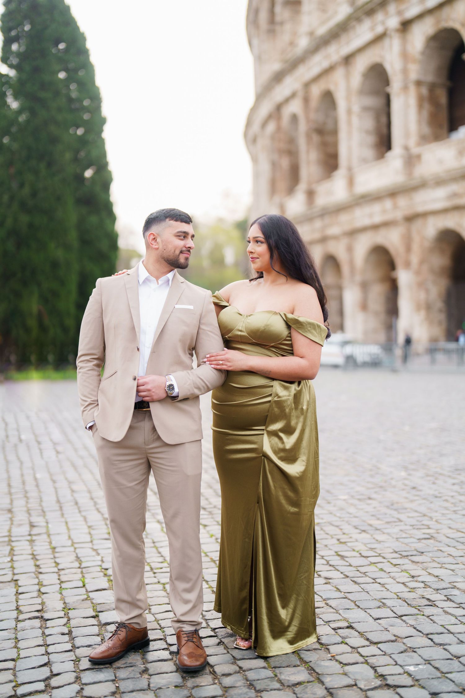 Elegant couple posing in formal attire before the Colosseum in Rome, Italy.