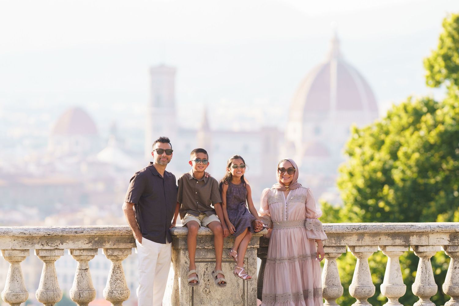 Family of four posing on a scenic terrace overlooking Florence skyline with the Duomo cathedral in background.