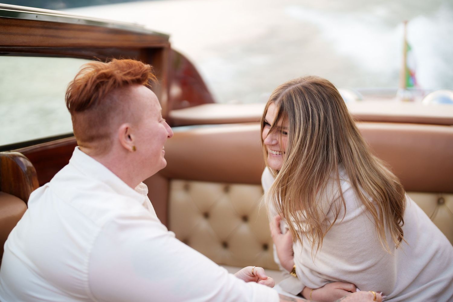 A smiling couple sharing a romantic moment seated in a vintage car with leather interior.