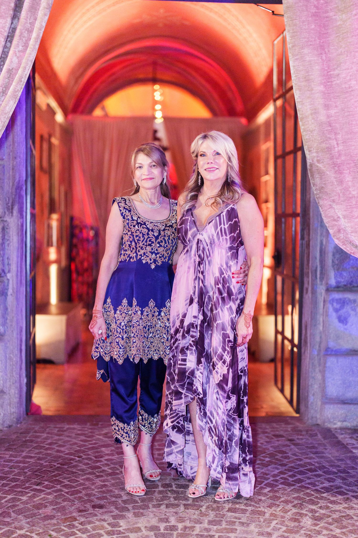 Two guests walking through a beautifully lit archway corridor with purple and orange ambient lighting.