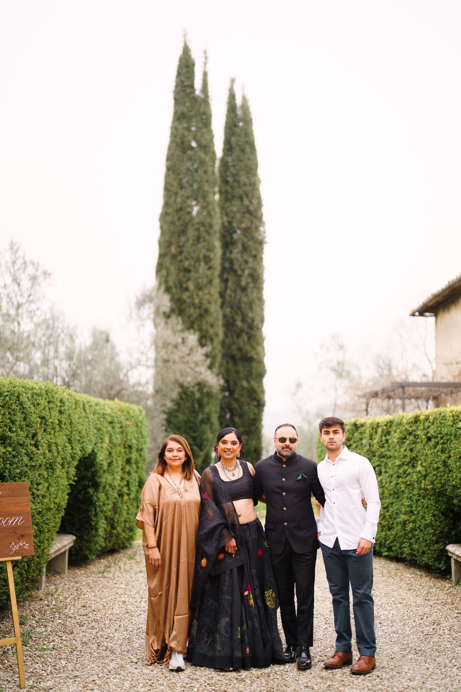 Casual group portrait on a gravel pathway surrounded by formal garden landscaping.
