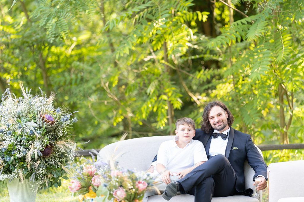 Elegant outdoor wedding ceremony setup with string lights and natural greenery backdrop.