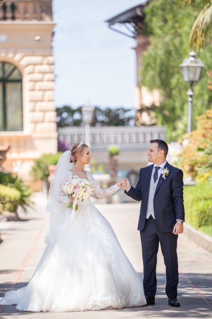 Wedding couple sharing a romantic moment on a Mediterranean terrace with stone architecture.