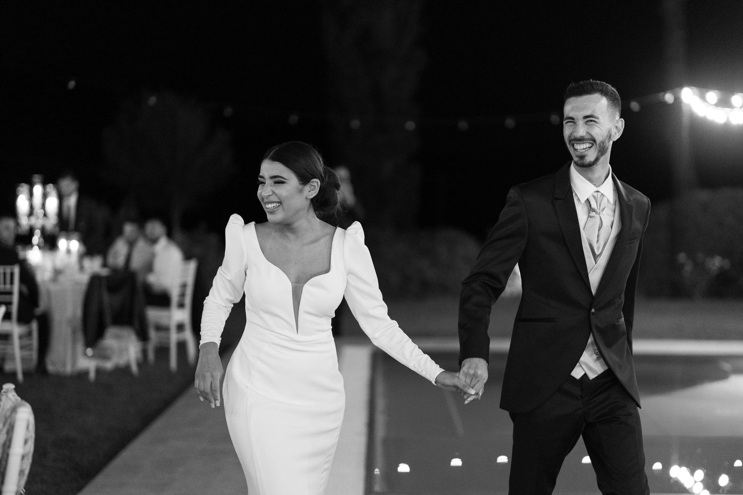 Couples dance together on an illuminated outdoor dance floor during an evening wedding reception.