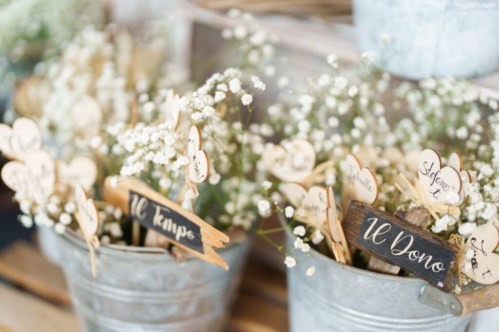 White baby's breath flowers arranged in rustic metal buckets with chalkboard signs for wedding decor.