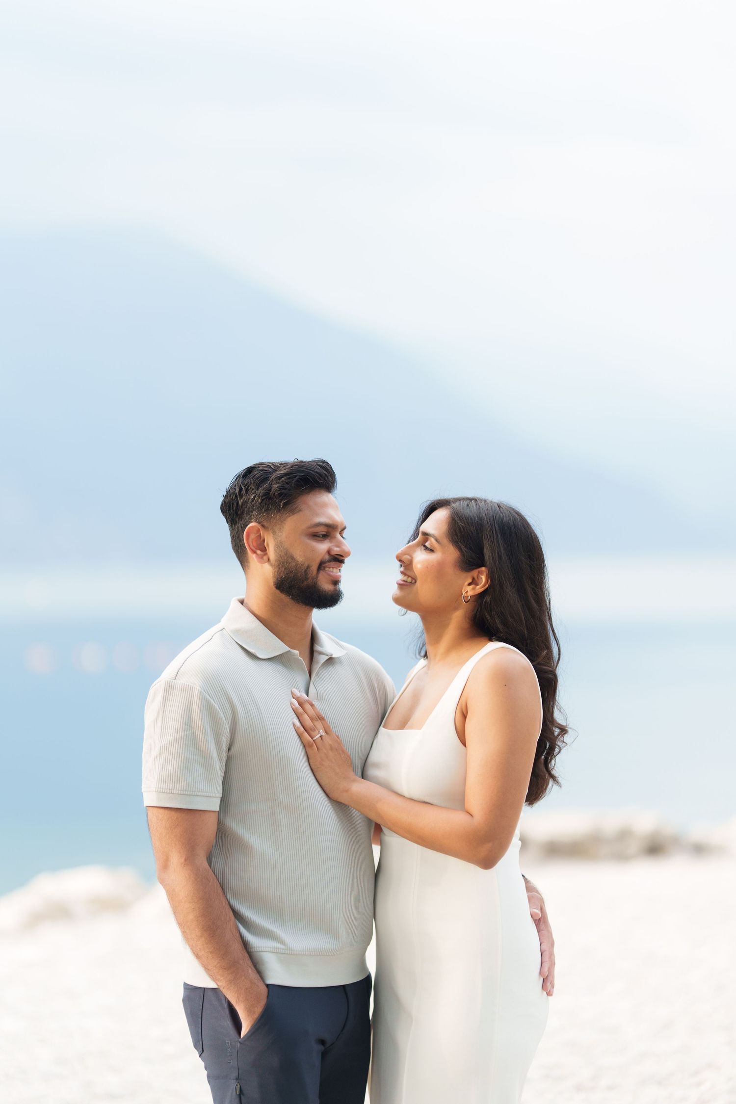 A couple shares joyful moments together during a romantic photoshoot on a misty beach.