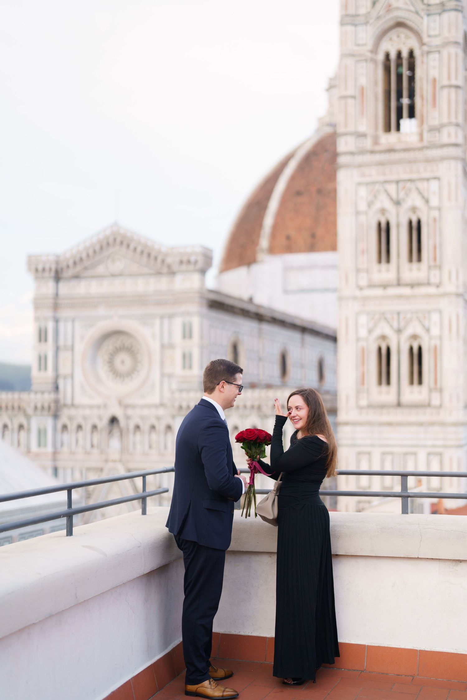 A couple shares a romantic moment on a rooftop terrace overlooking the Florence Cathedral and Duomo in Italy.