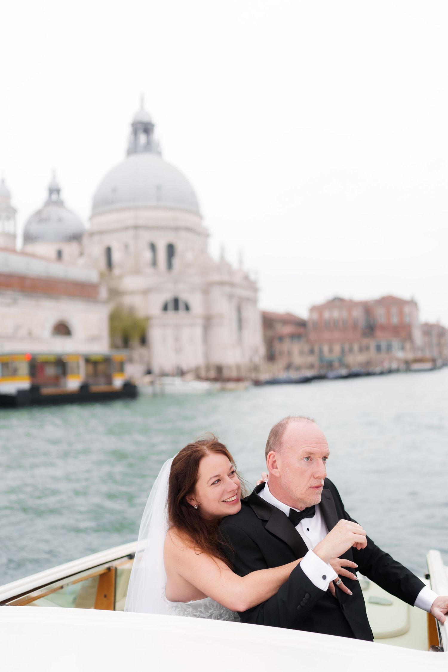 Couple sharing romantic moments on a water taxi in Venice with the iconic Santa Maria della Salute church in background.