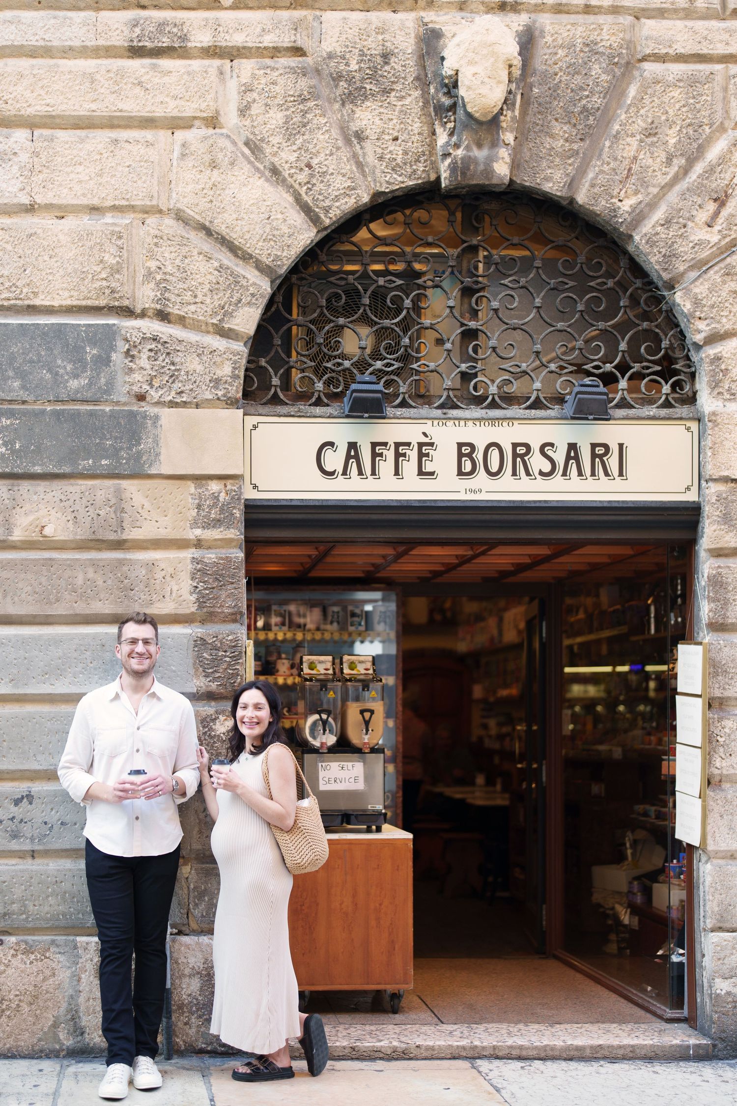 A series of archway entrances to Caffe Borsari with decorative iron grillwork above stone doorways.