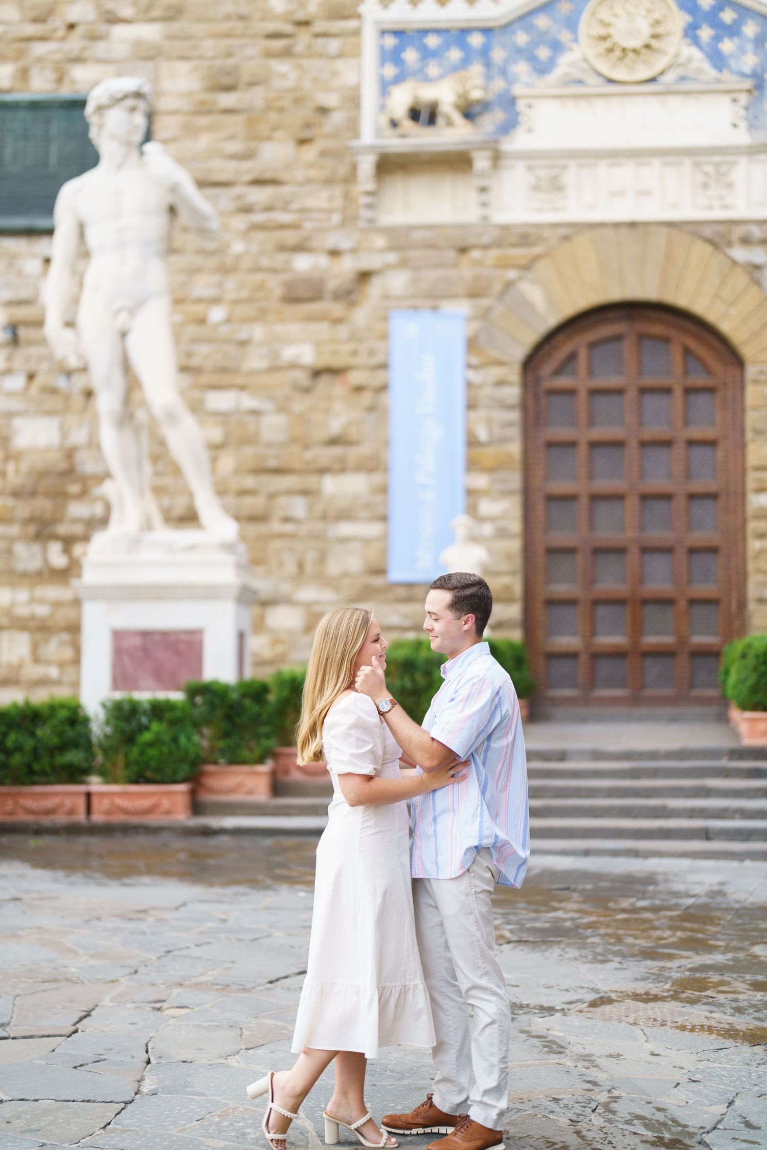 A couple shares a romantic moment during a proposal outside a historic stone building in Florence, Italy.