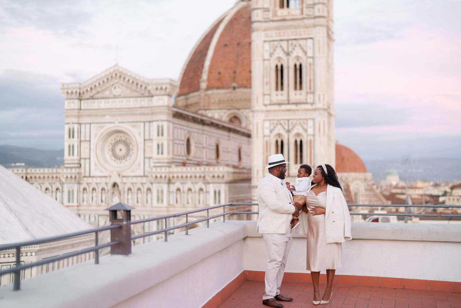 Couple in white outfits on a rooftop terrace with Florence Cathedral dome in the background.