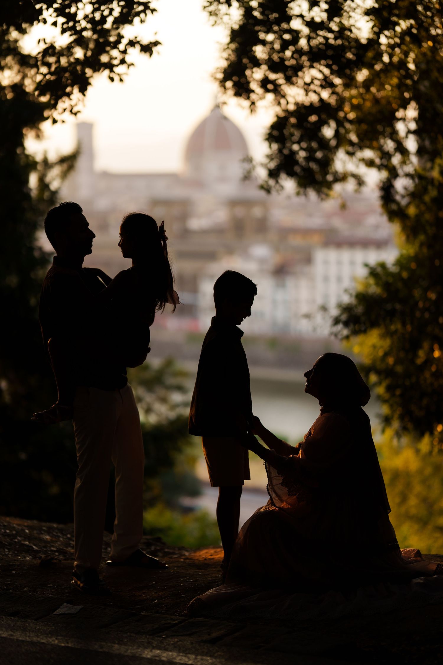 Silhouettes of a family against Florence skyline with Duomo cathedral at sunset.