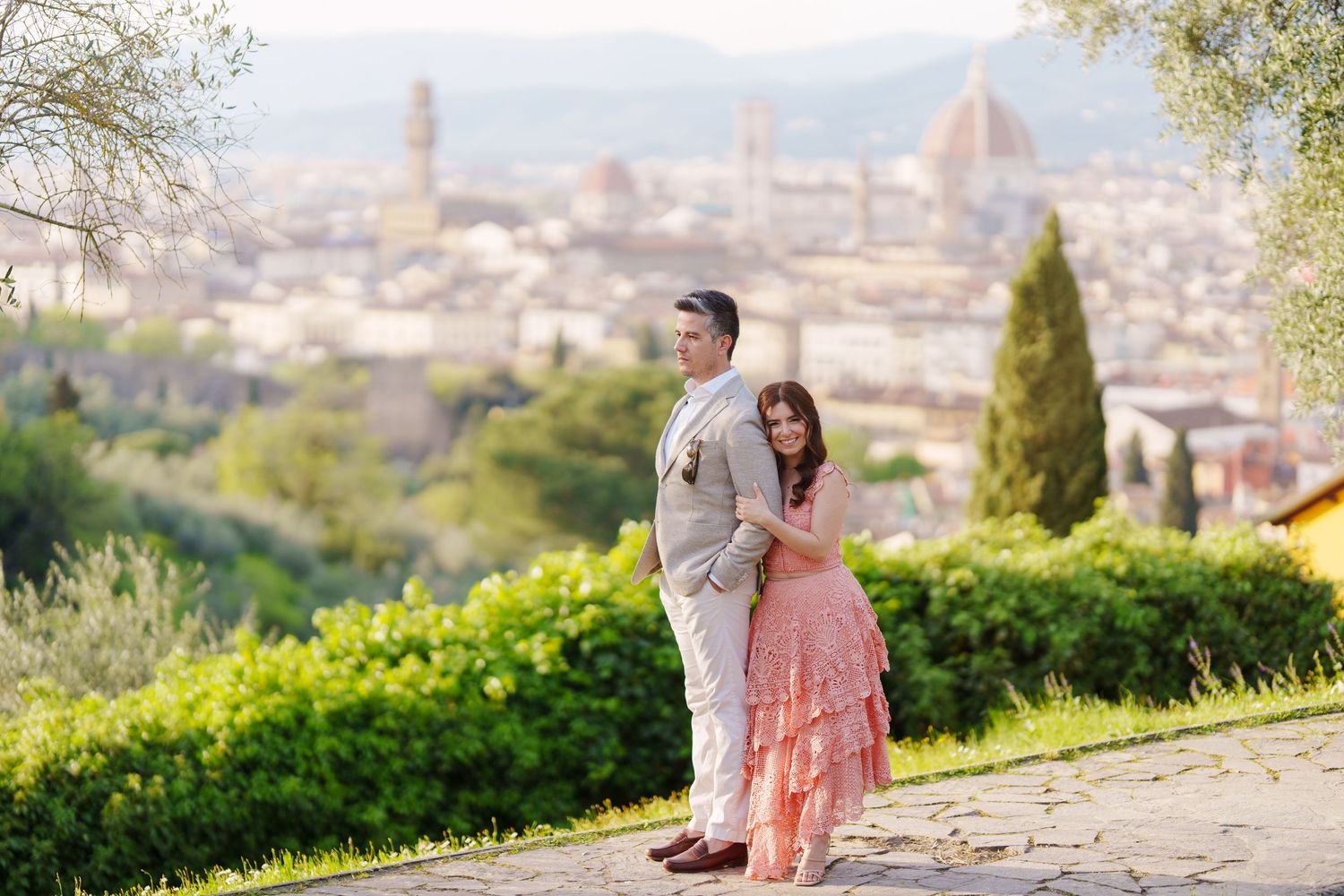 Romantic couple enjoying panoramic views of Florence, Italy from Piazzale Michelangelo during golden hour.