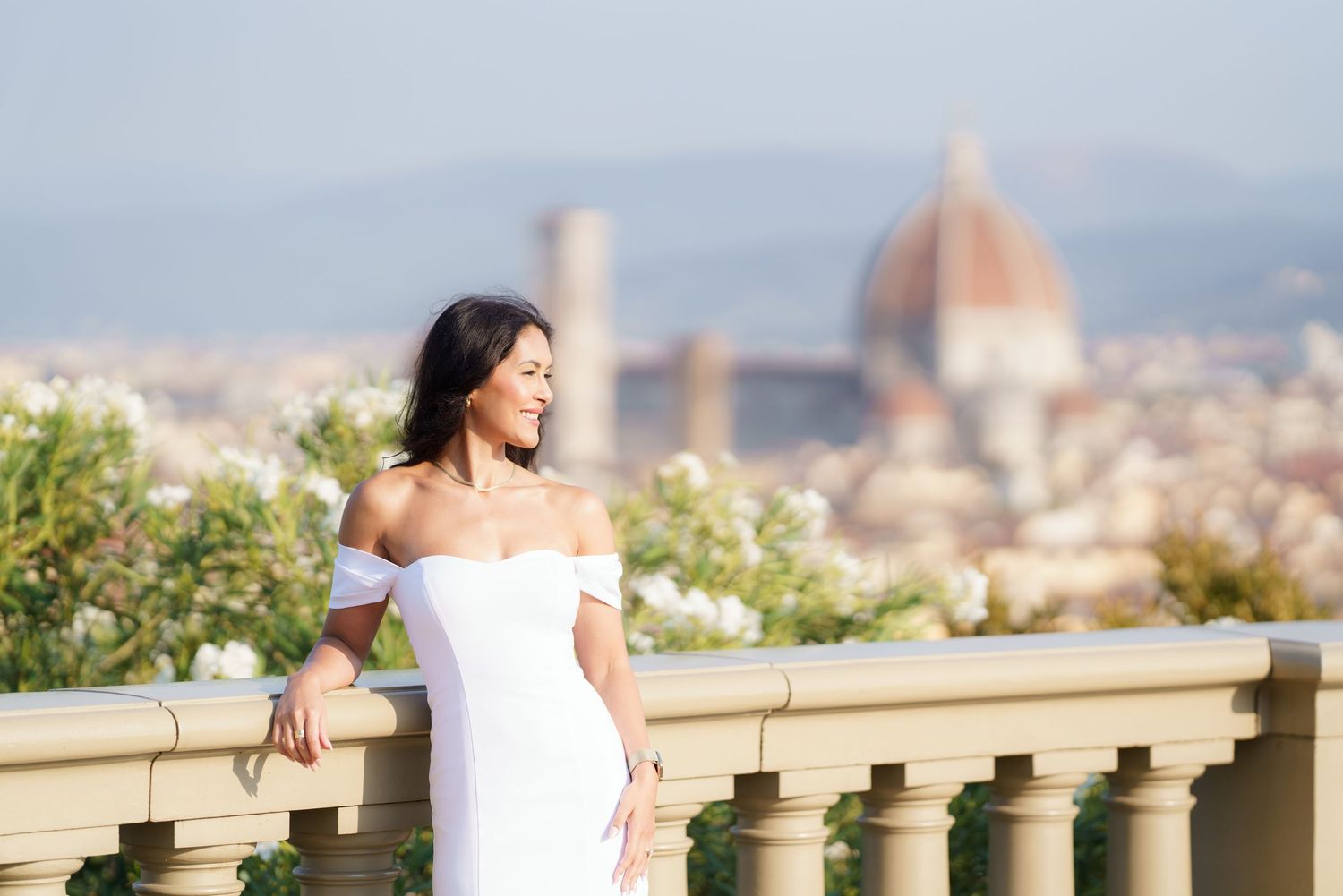 Woman in white dress admires panoramic view of Florence cityscape with Duomo cathedral in background.