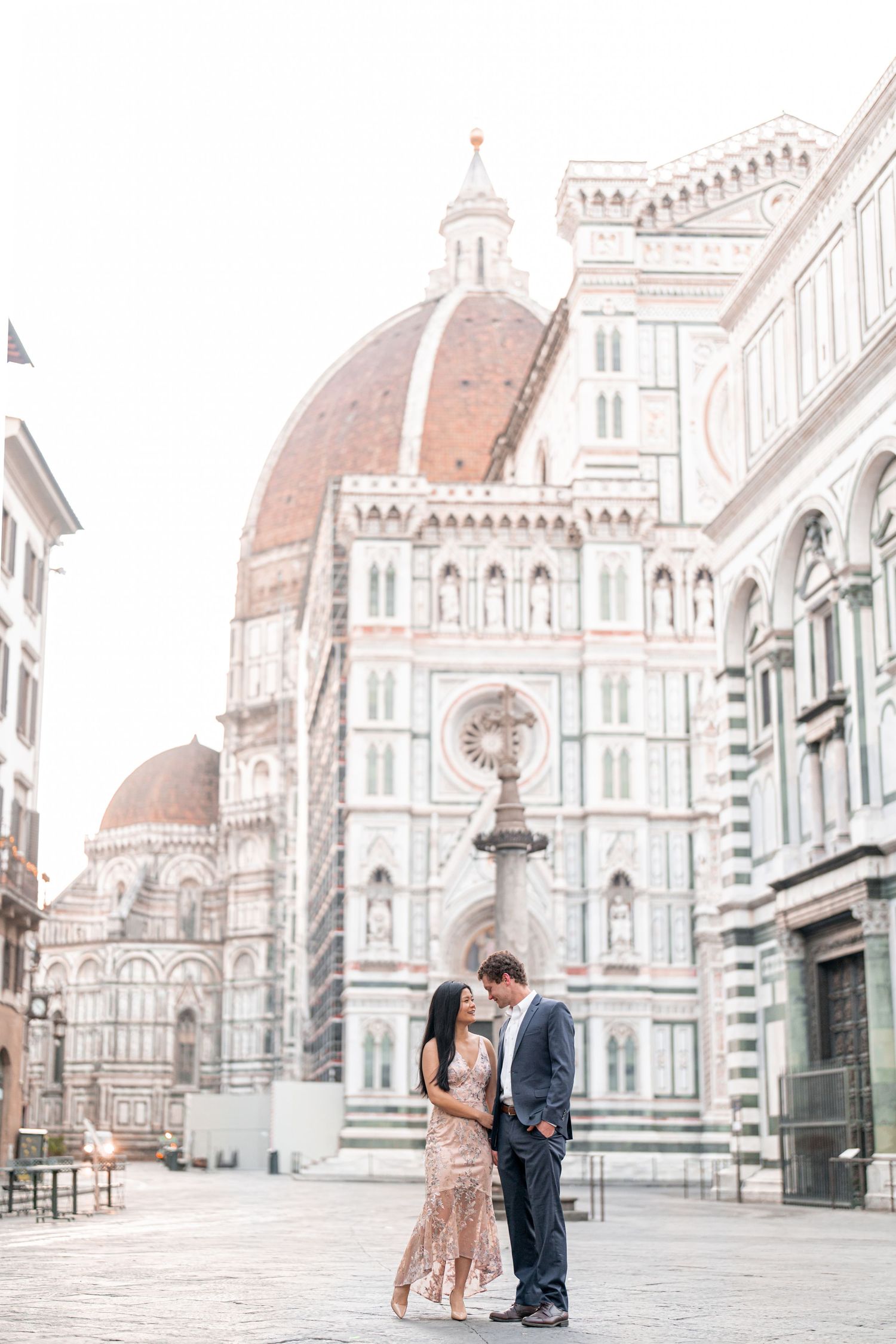 A couple shares a romantic moment in front of the iconic Florence Cathedral (Duomo) in Italy during sunrise.