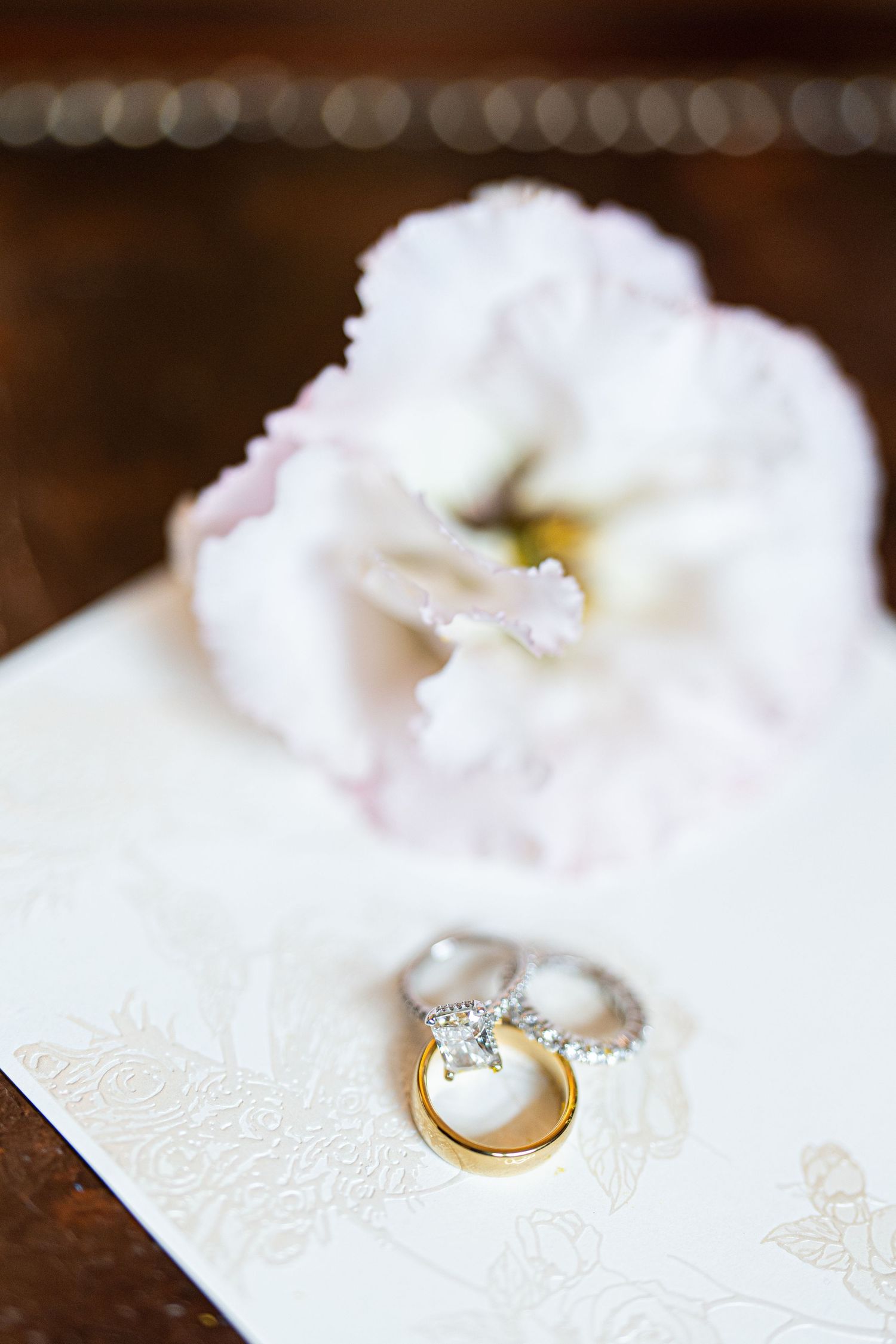 Wedding rings and pearl jewelry arranged on white lace fabric.