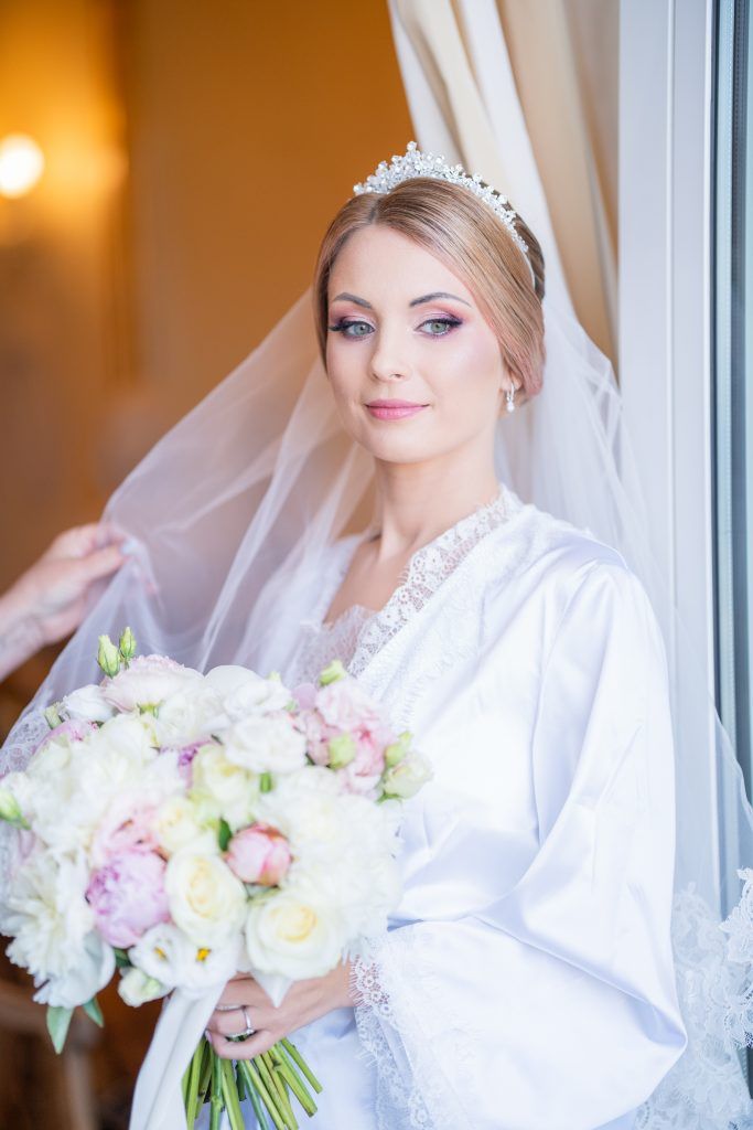 Bridal portrait series showing white robe and delicate bouquet of mixed pastel flowers.