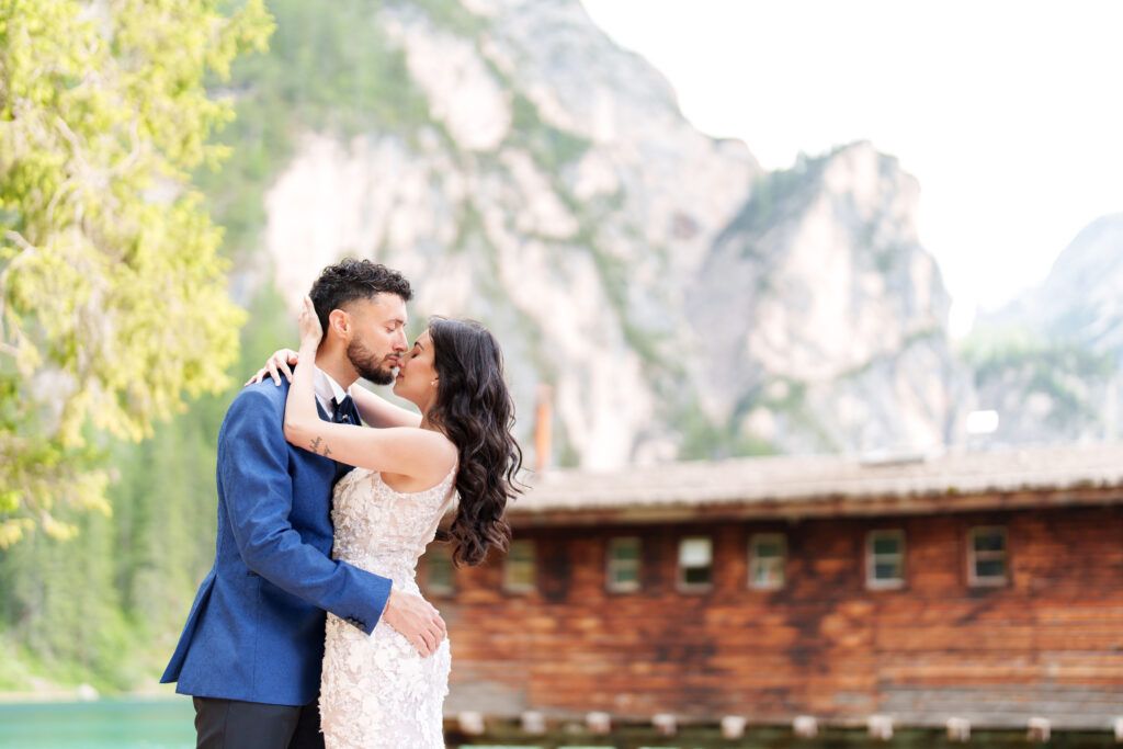 A couple shares an intimate moment during their mountain wedding photoshoot by an alpine lake.