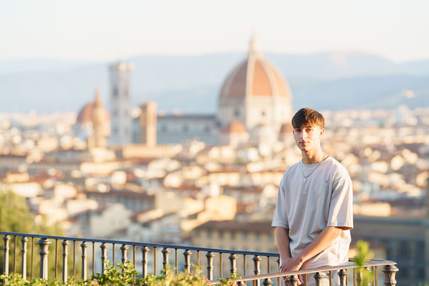 Tourist enjoying panoramic views of Florence cityscape from Piazzale Michelangelo viewpoint during sunset.