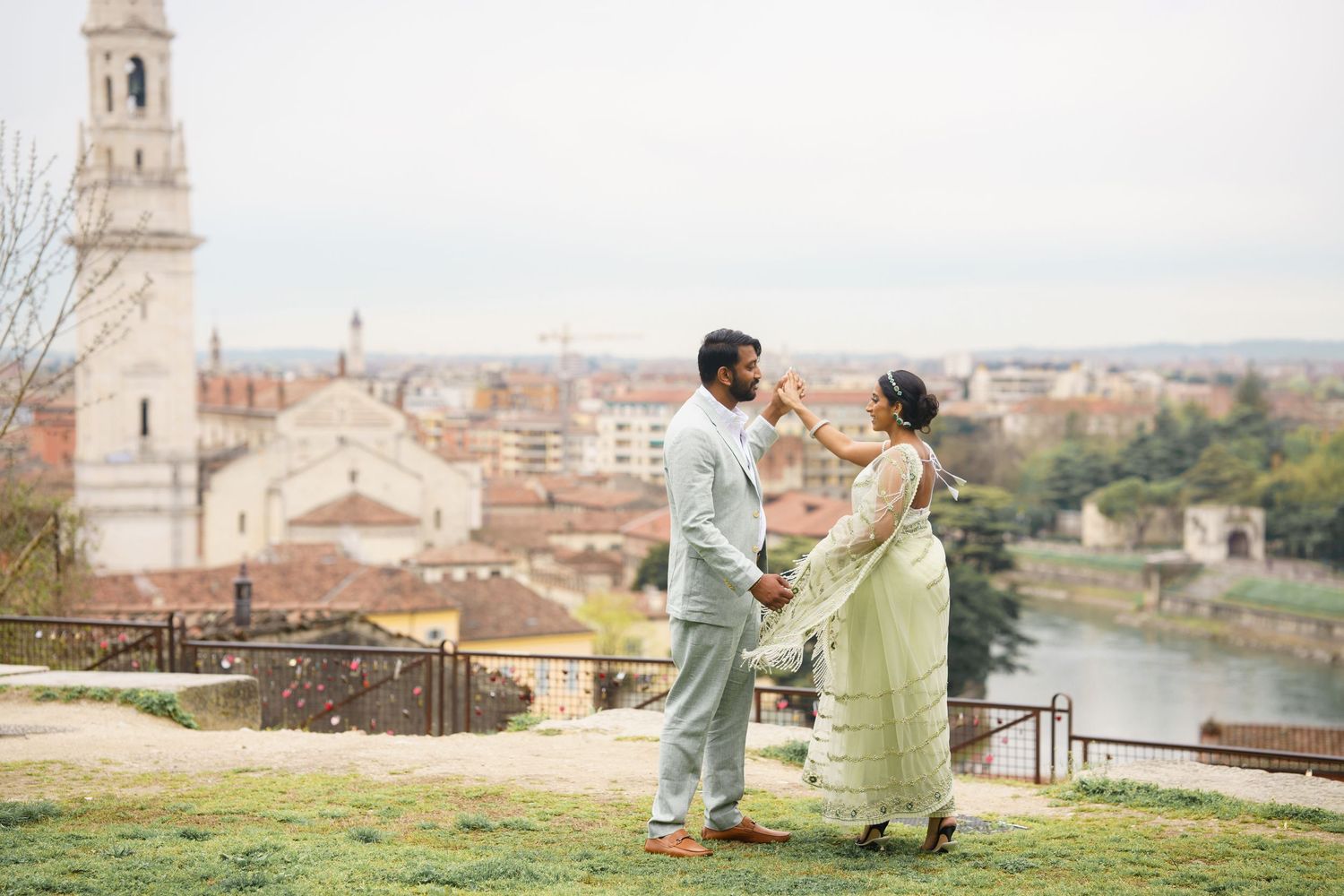 Couple in pastel outfits sharing romantic moments against historic Italian architecture and city views.