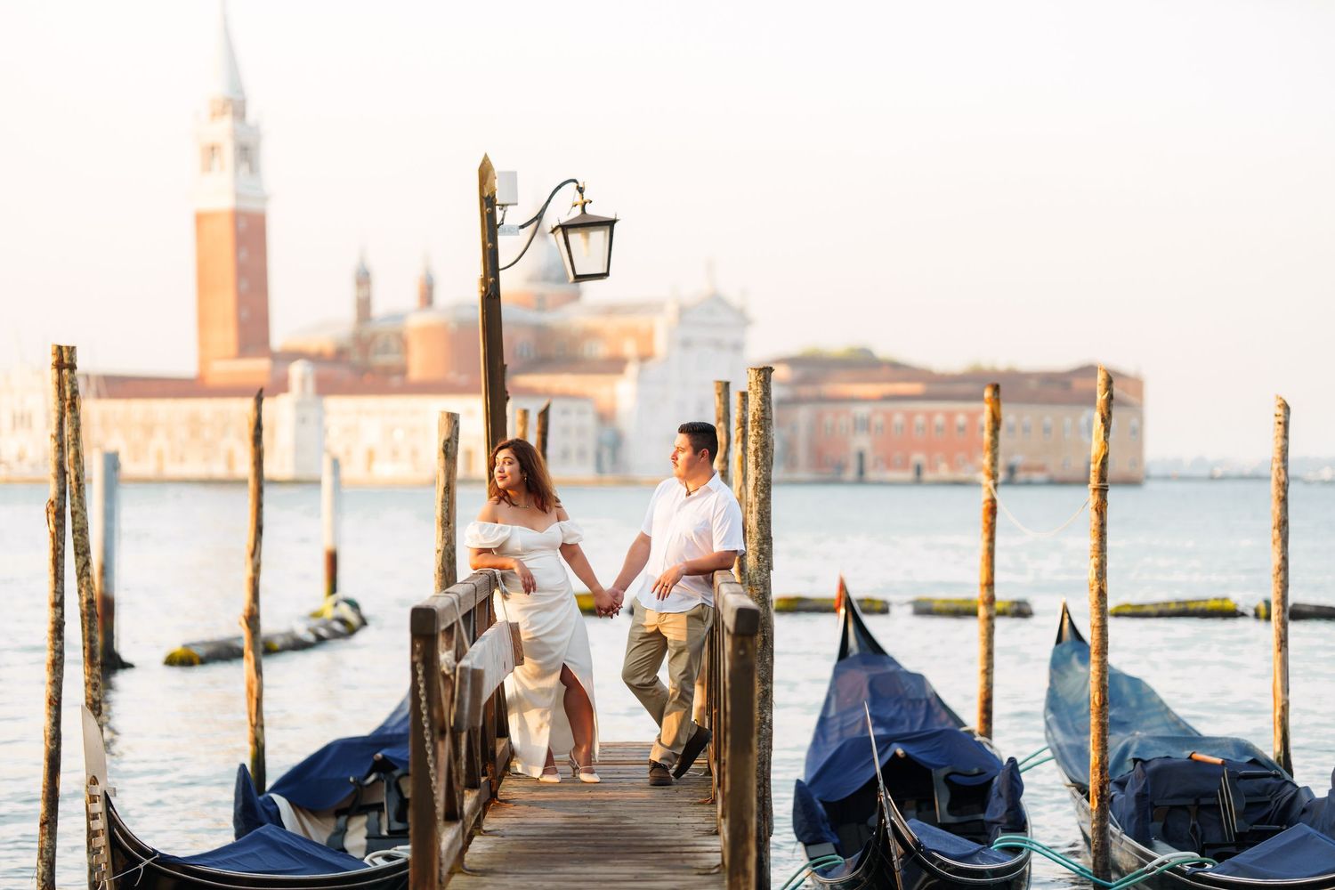 photographer venice Gondolas moored at wooden posts along Venice's waterfront with the iconic skyline and church domes in the background.