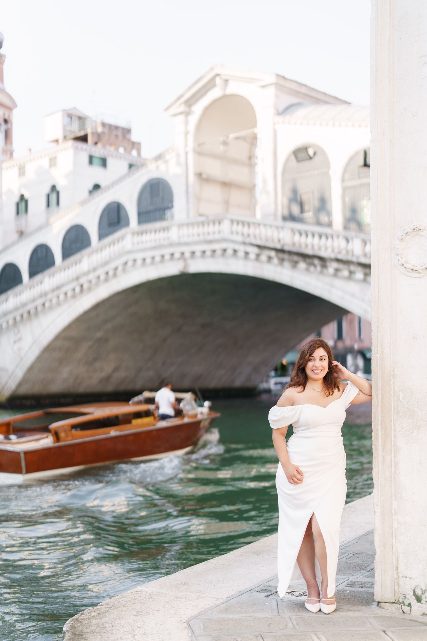 A romantic scene by a Venetian canal with stone bridges and wooden boats floating on turquoise water.