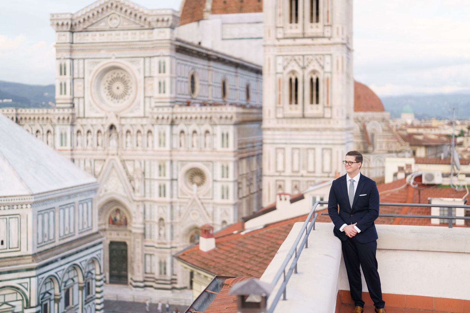 Scenic view of Florence Cathedral's ornate facade and bell tower with couple on rooftop terrace in Italy.