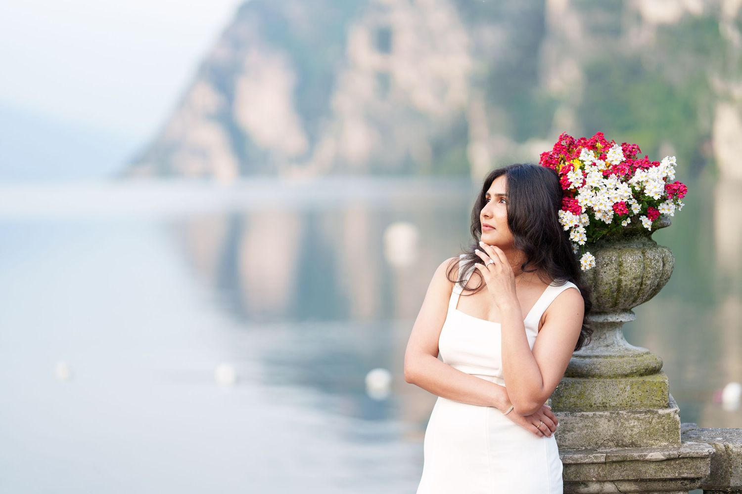 A romantic outdoor bridal portrait session features a floral crown and elegant white dress against a stone backdrop.