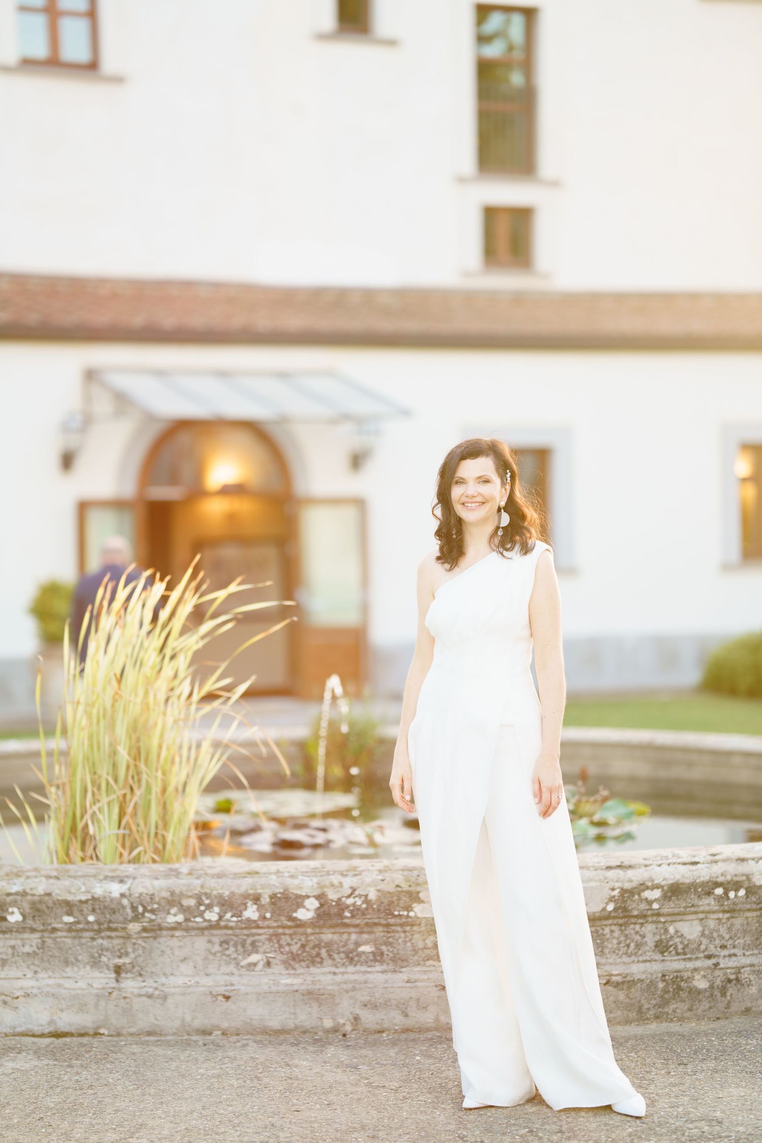White wedding dress photographed against stone wall and white building exterior.