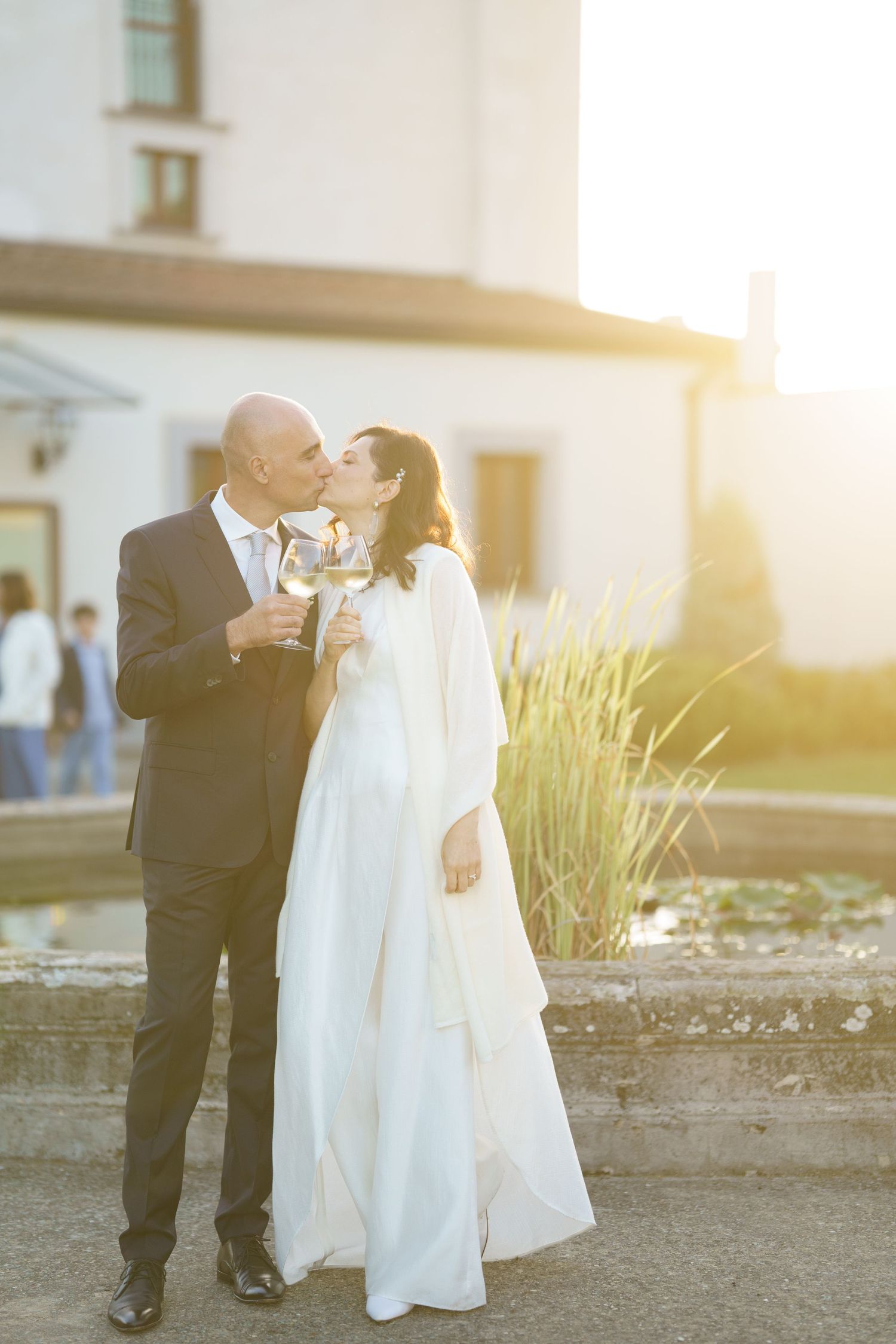 Newlyweds share an intimate toast in their wedding attire during sunset.