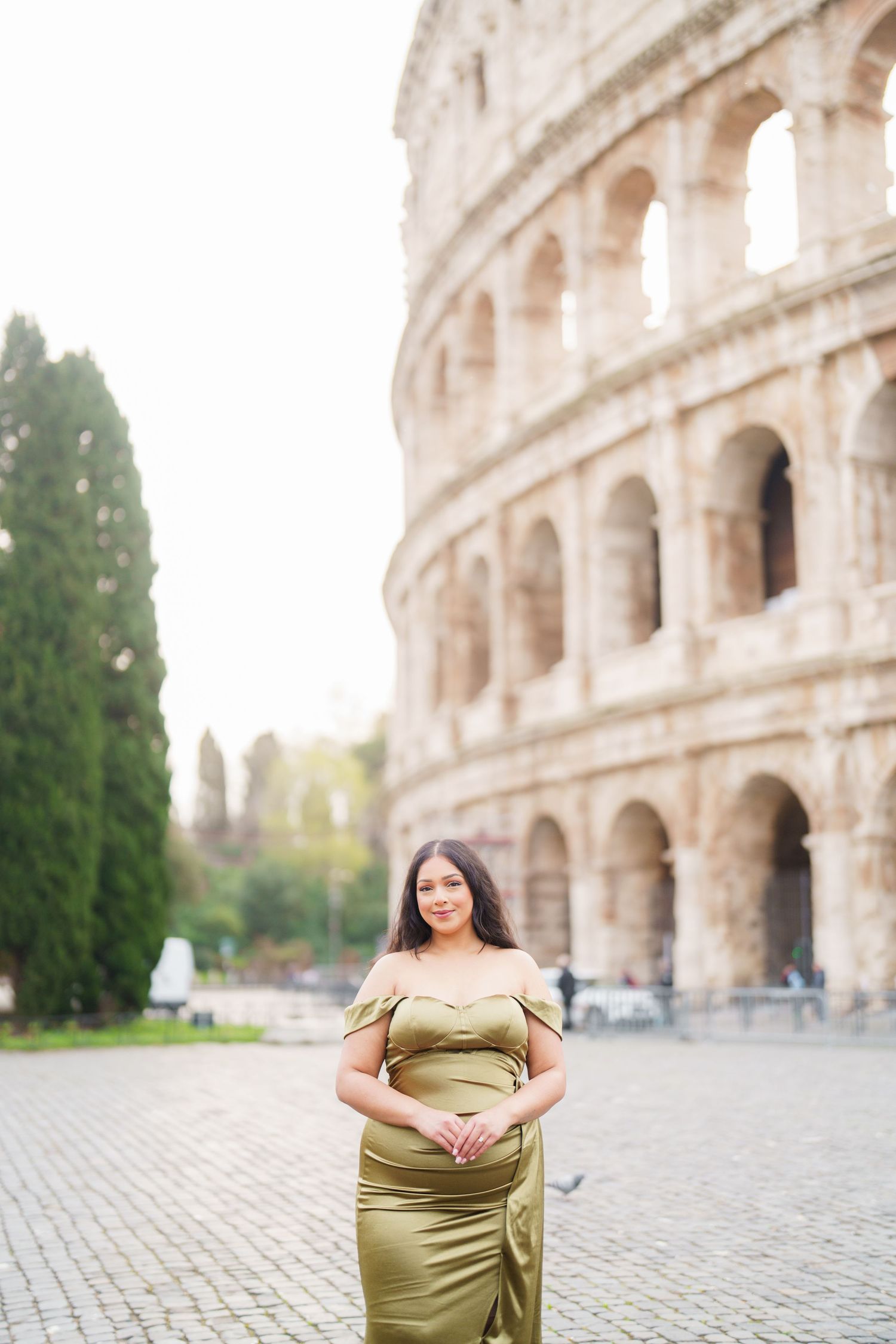 Pregnant woman in olive green gown posing before the Colosseum in Rome, Italy.