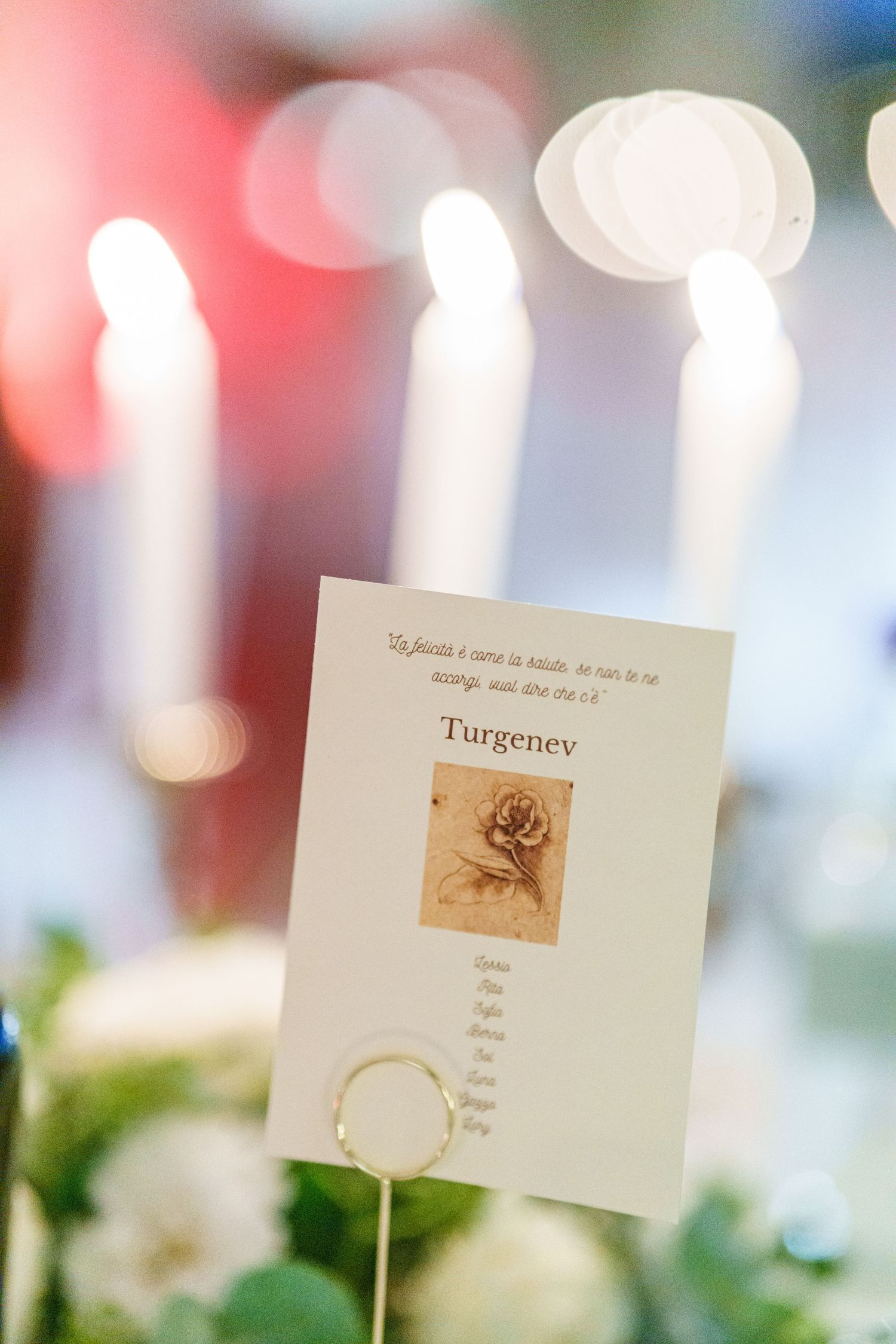 Wedding table place cards with decorative designs displayed among candles and floral arrangements.