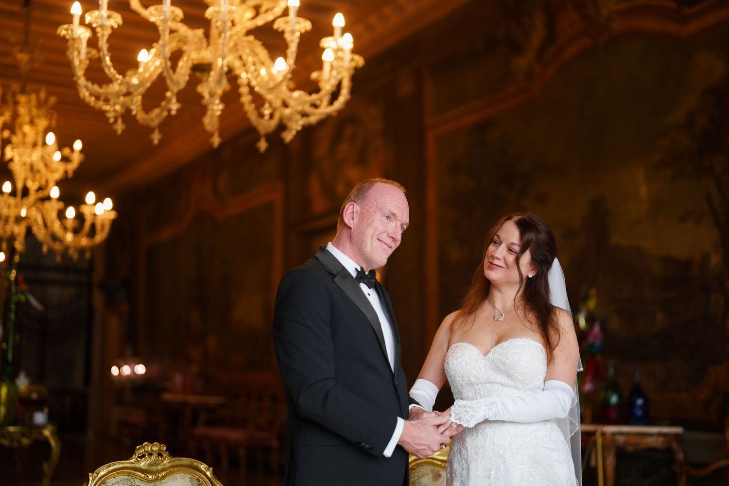 A couple shares their first dance at a wedding reception under elegant crystal chandeliers in a grand ballroom.