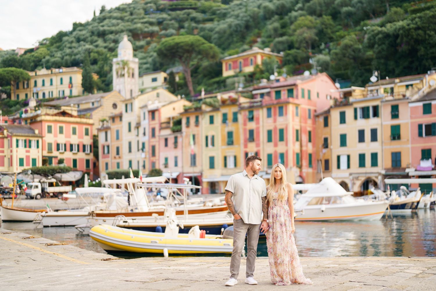 Colorful pastel buildings line the waterfront of Portofino, Italy with boats docked in the Mediterranean harbor.