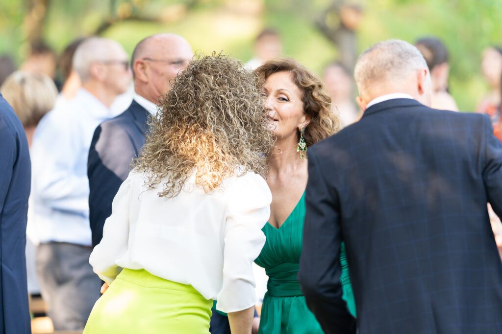 Guests in formal attire socialize during an outdoor wedding celebration.
