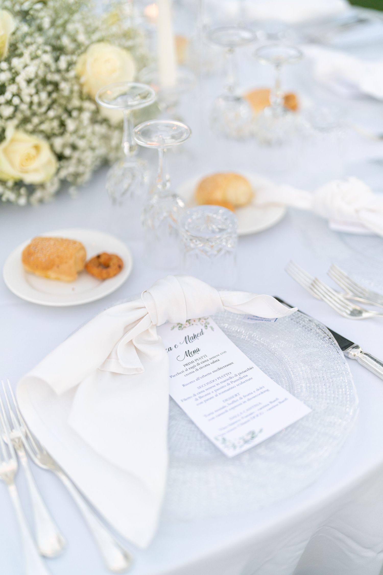 Close-up of elegant place settings with menu cards and white napkins at a wedding reception.