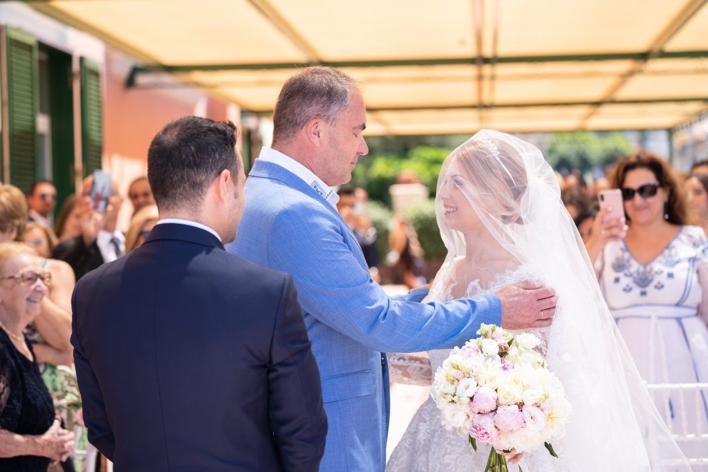 Wedding guests celebrate during an outdoor reception under a white canopy.