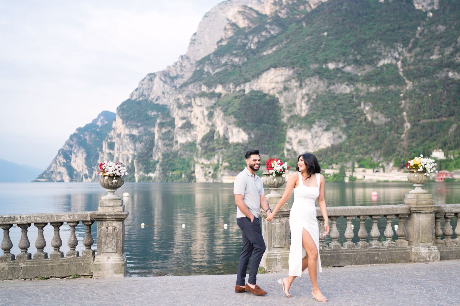 Couple enjoying a romantic moment on a scenic lakeside terrace with mountains and water views in the background.