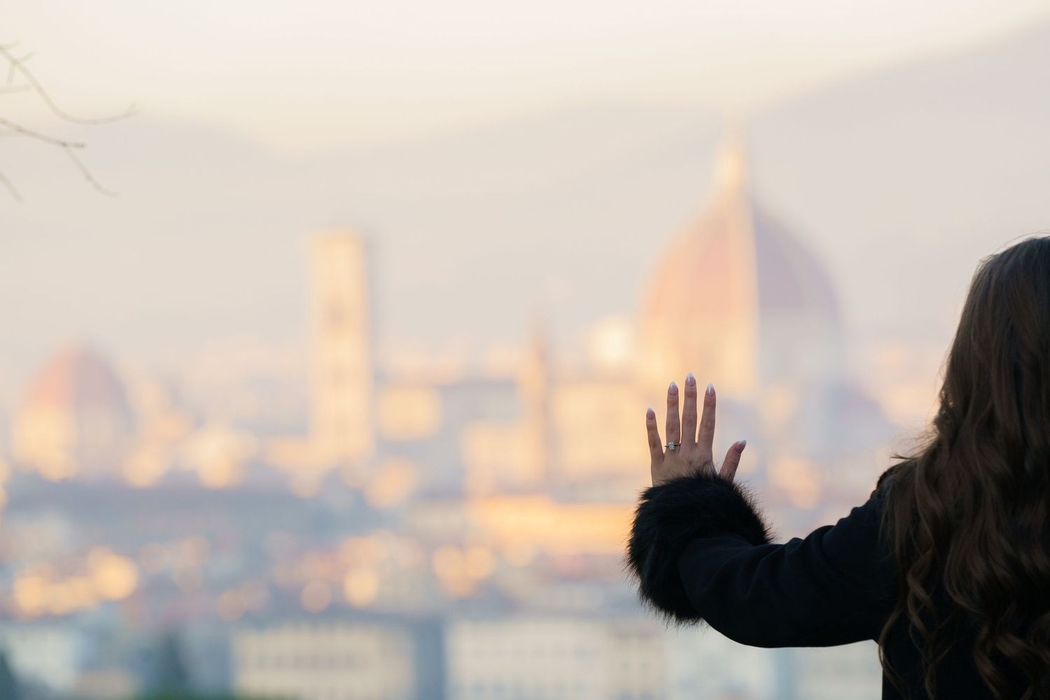 Silhouetted figures stand against a blurry cityscape background with warm glowing lights at sunset.