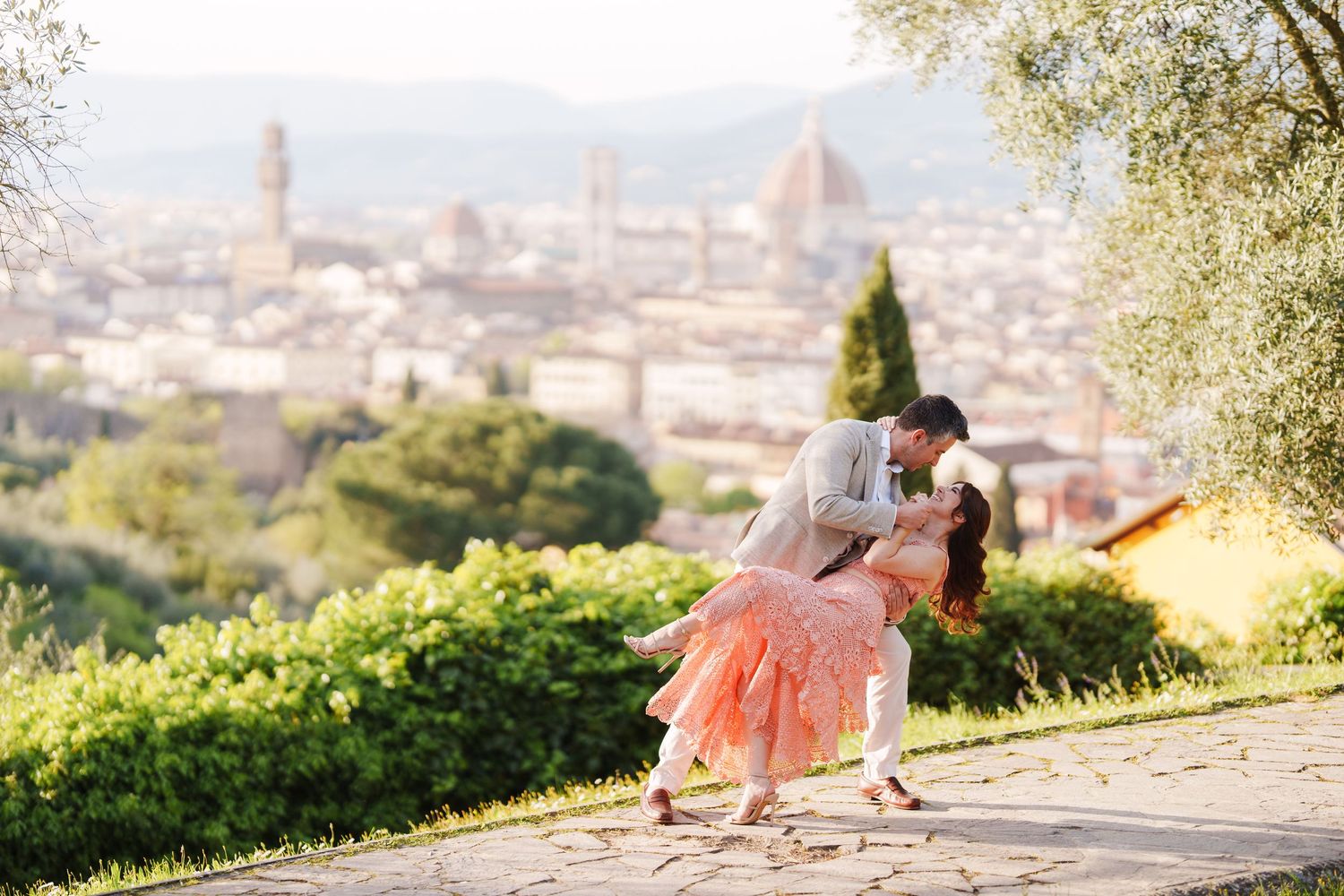 A romantic couple shares a tender moment overlooking the scenic cityscape of Florence, Italy at sunset.