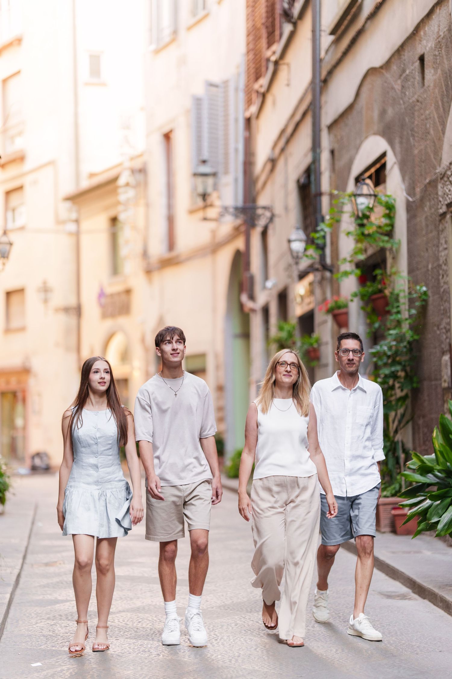 Group wearing coordinated white outfits walking together down a charming European street in summer.