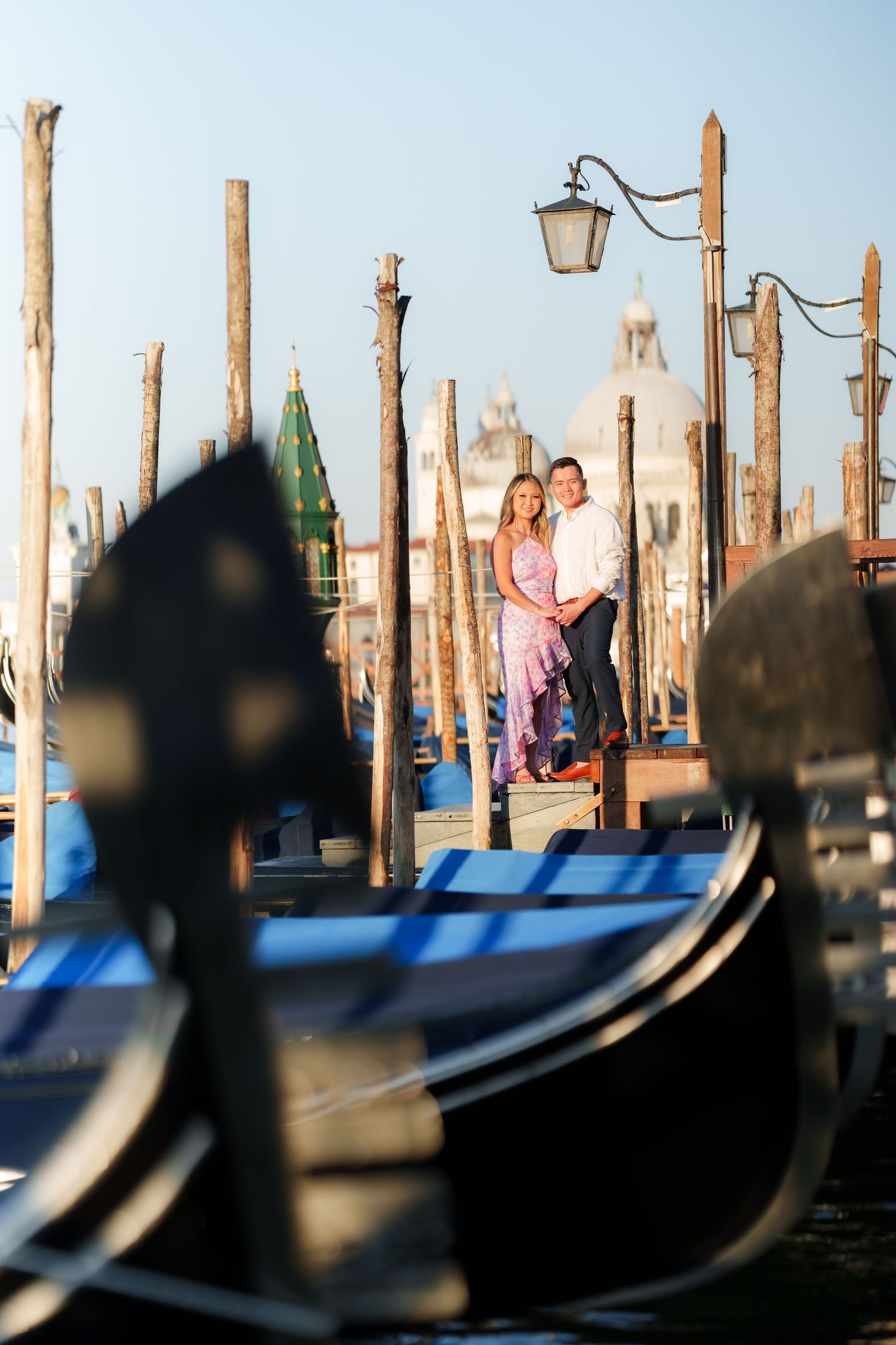 Couple embracing among Venice gondolas with San Giorgio Maggiore church in the golden hour background.