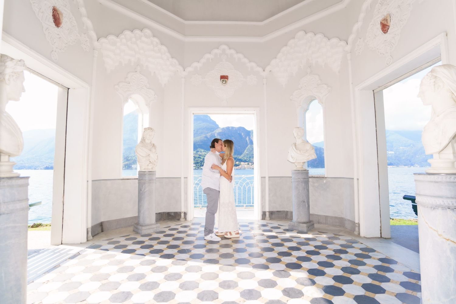 White marble arches and blue checkered floor create a stunning architectural corridor with mountain views in the background.