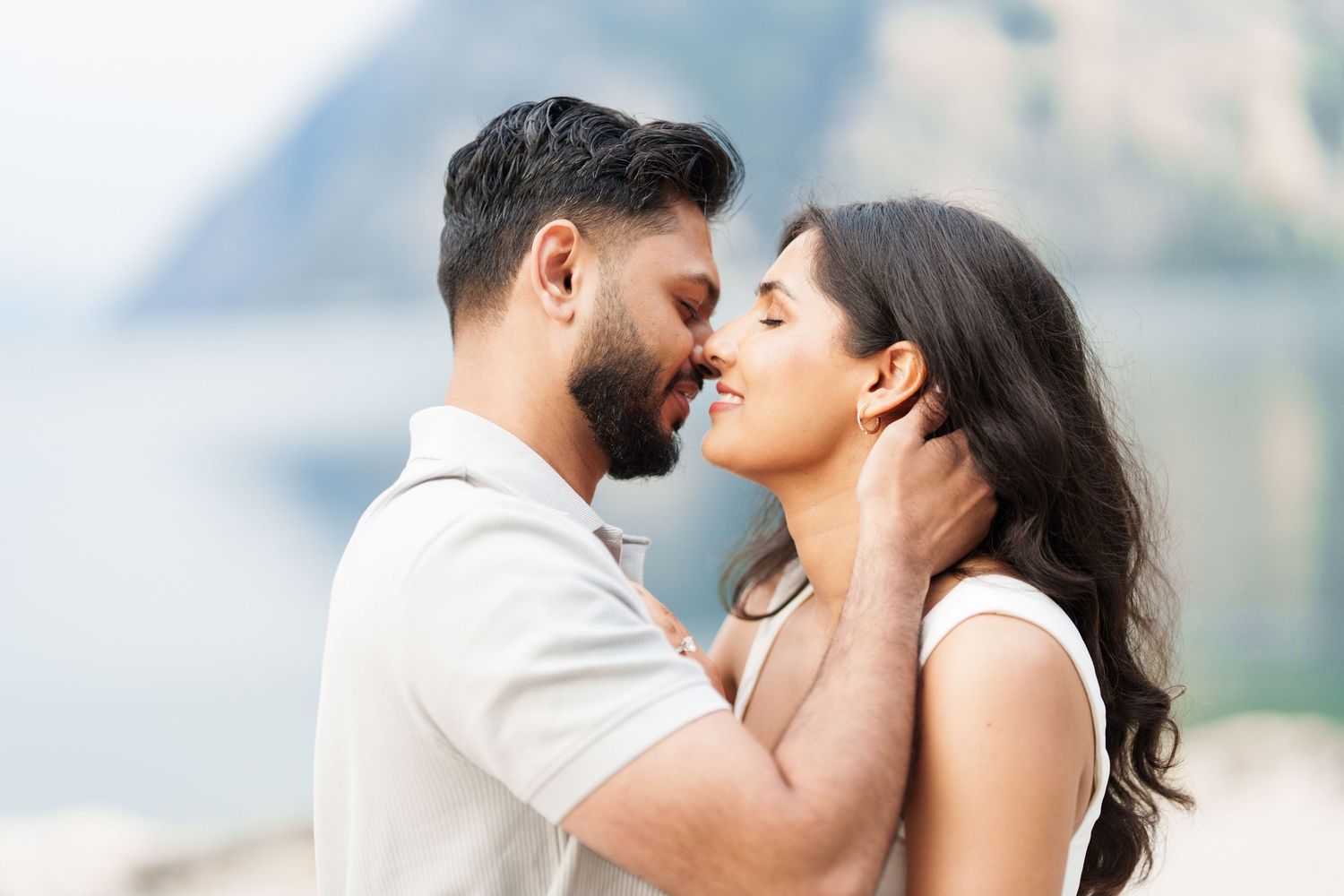 A romantic couple shares tender kisses in a series of outdoor photos against a blurred mountain backdrop.