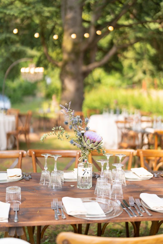 Rustic wooden tables set for an outdoor wedding reception with delicate floral centerpieces.