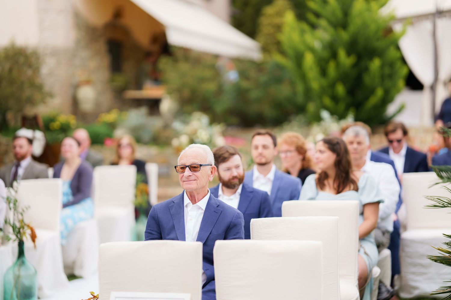 Elegant outdoor wedding reception setup with white chairs and tables under a covered patio.